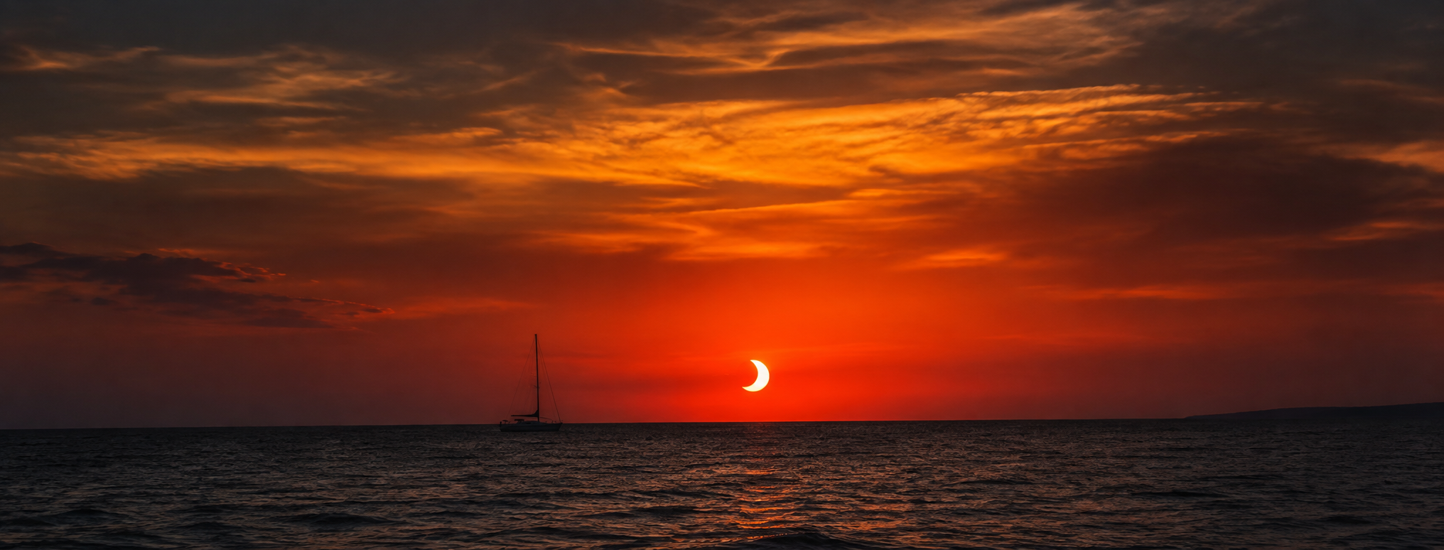 Solar eclipse over the ocean at sunset