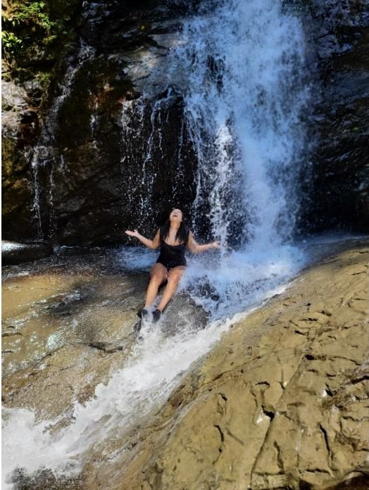 Woman sitting beneath a waterfall